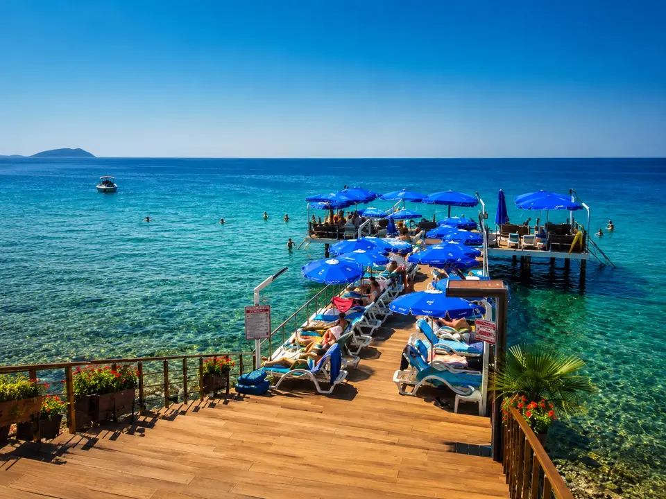 Grand Koru Otel Beach iskelesi: mavi şemsiyeler, şezlonglar ve arkada Marmara Denizi