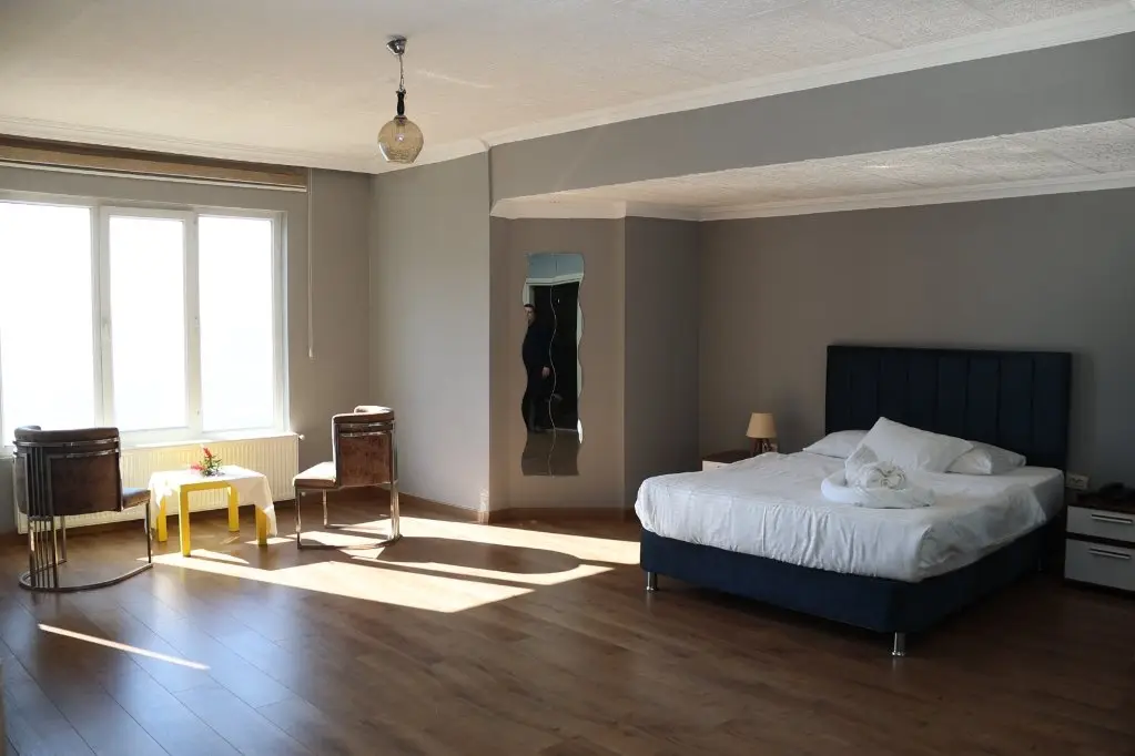 Deluxe odada çift kişilik yatak ve geniş pencereler